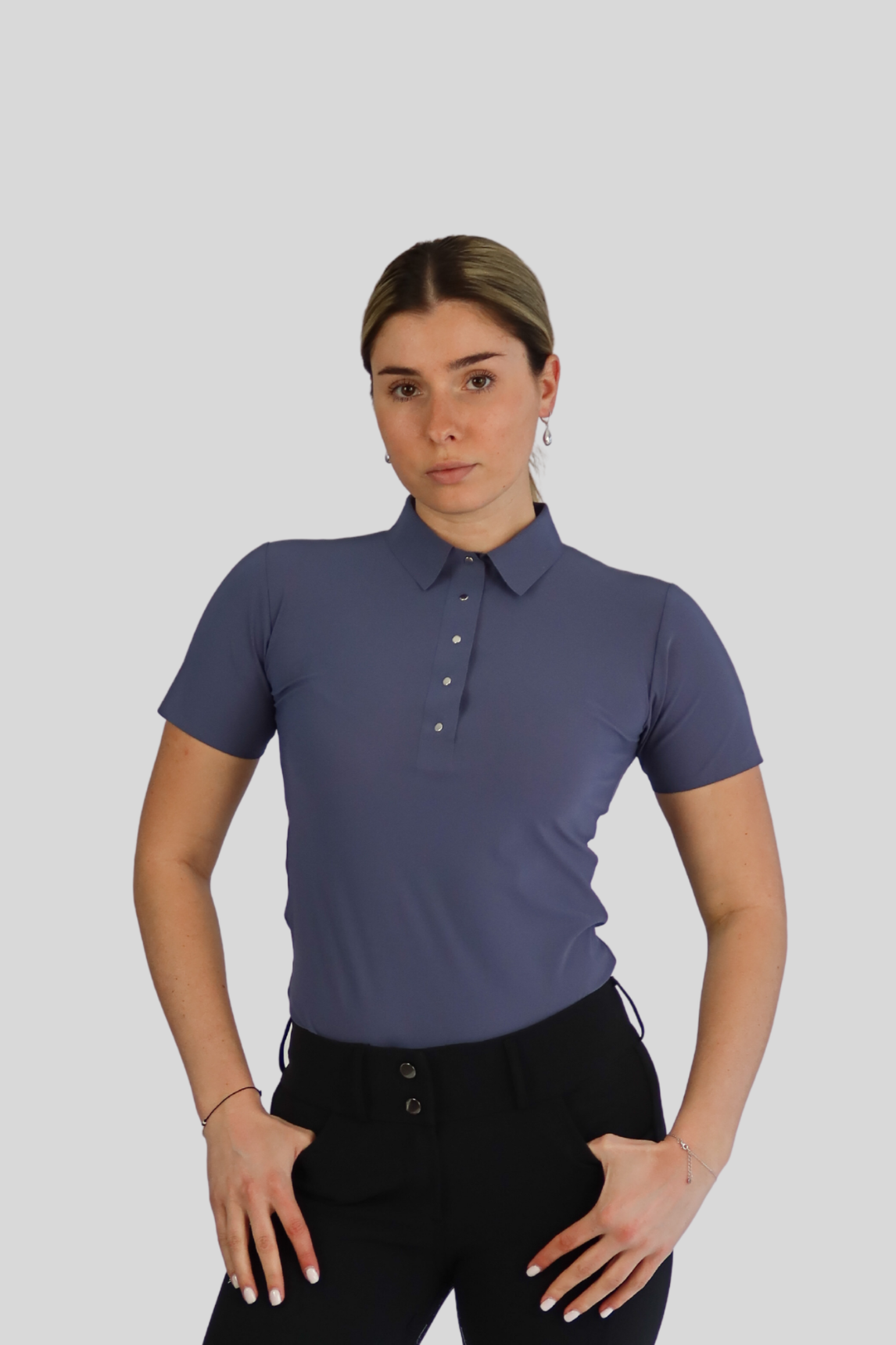 Woman wearing a blue polo shirt and black leggings on a white background
