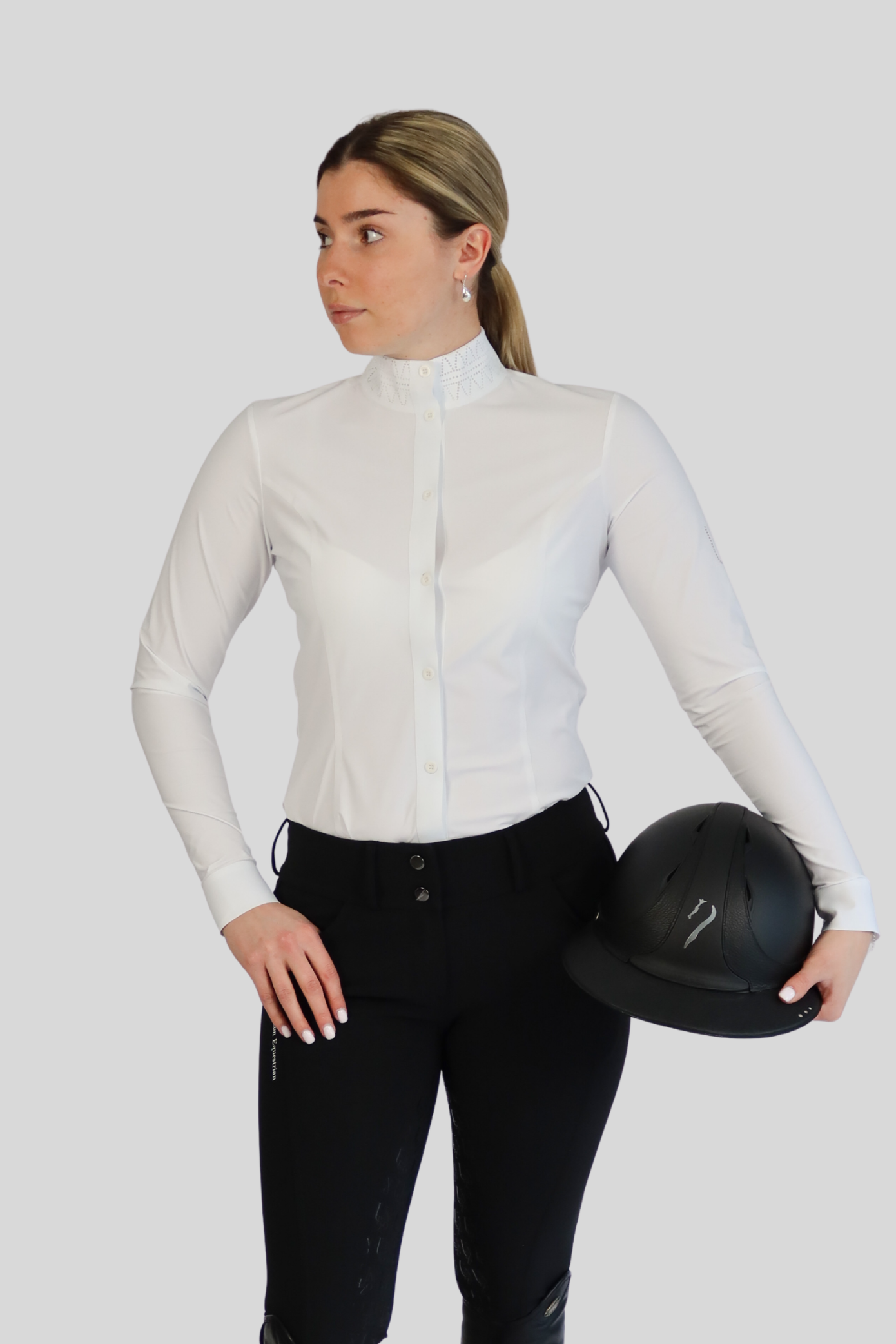 Woman in equestrian attire holding a helmet on a white background