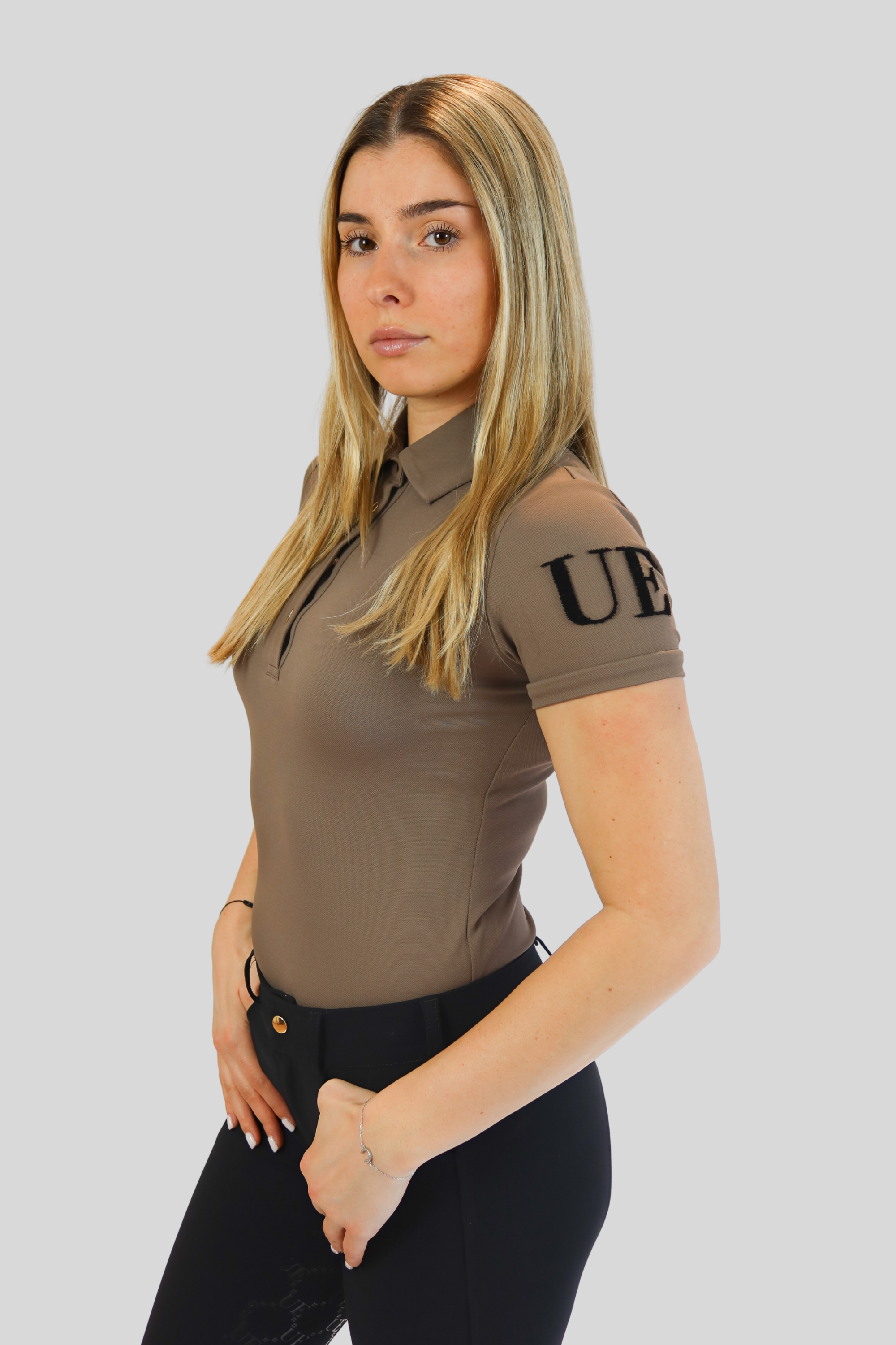 Woman wearing a brown polo shirt with 'UE' logo on a gray background
